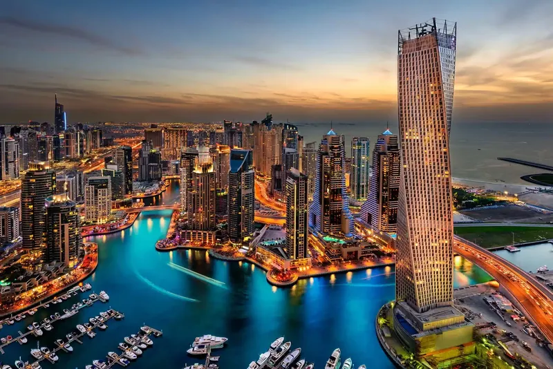 أبراج دبي مارينا والمرسى مضاءة عند الغروب